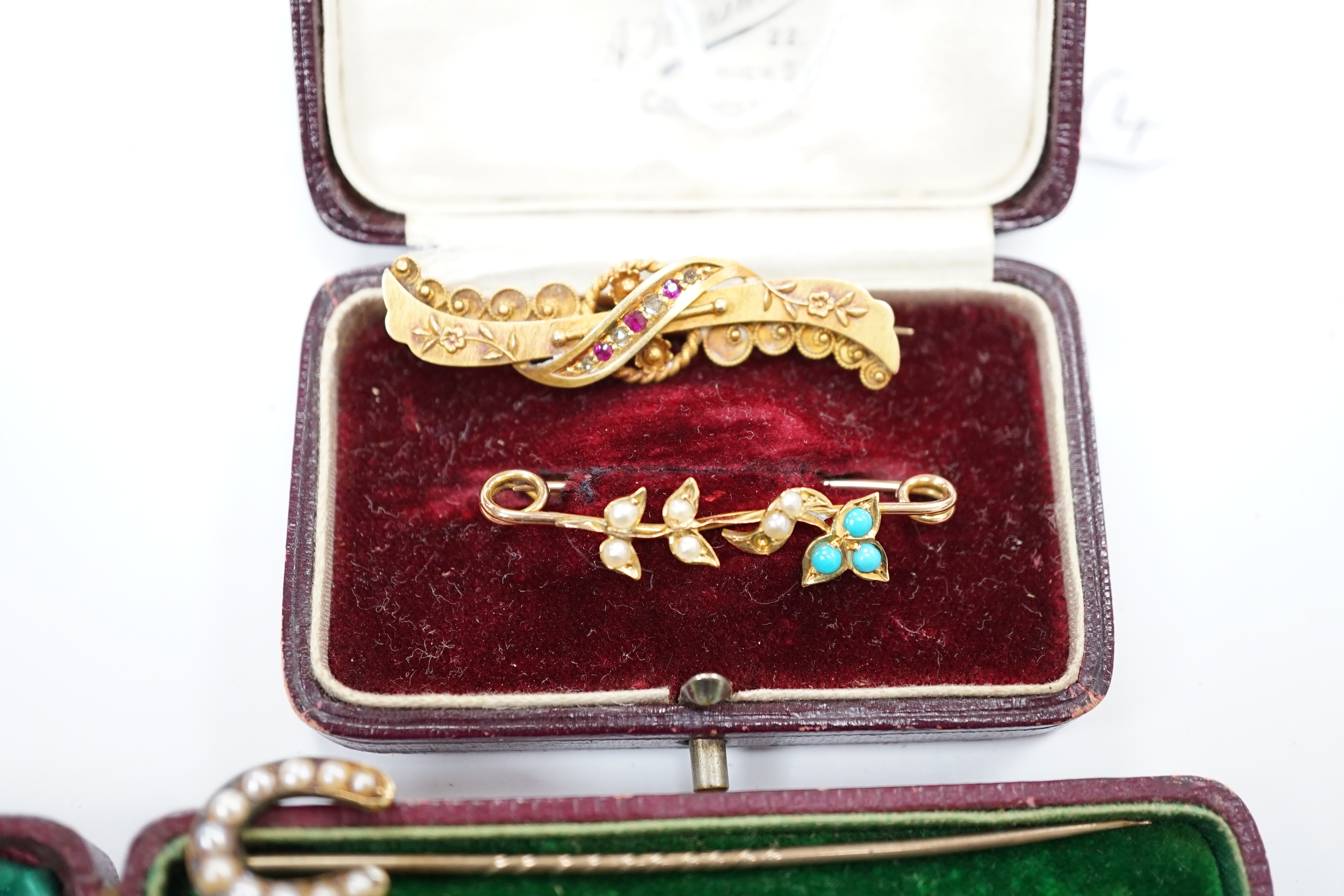 A late Victorian 15ct gold, ruby and diamond chip set bar brooch, 39mm, a yellow metal, seed pearl and turquoise set bar brooch and two seed pearl set horseshoe stick pins, one stamped 9ct, the other 18. Condition - fair